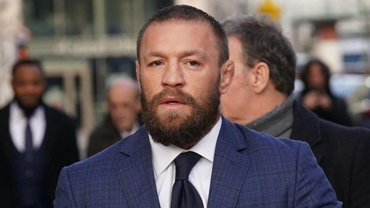Conor McGregor wearing a blue shirt, white shirt and black tie. He has light brown short hair and a beard Conor McGregor wearing a blue shirt, white shirt and black tie. He has light brown short hair and a beard